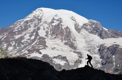 "A silhouetted hiker traverses a ridge in the Tatoosh Range in Mt. Rainier National Park, Washington State."